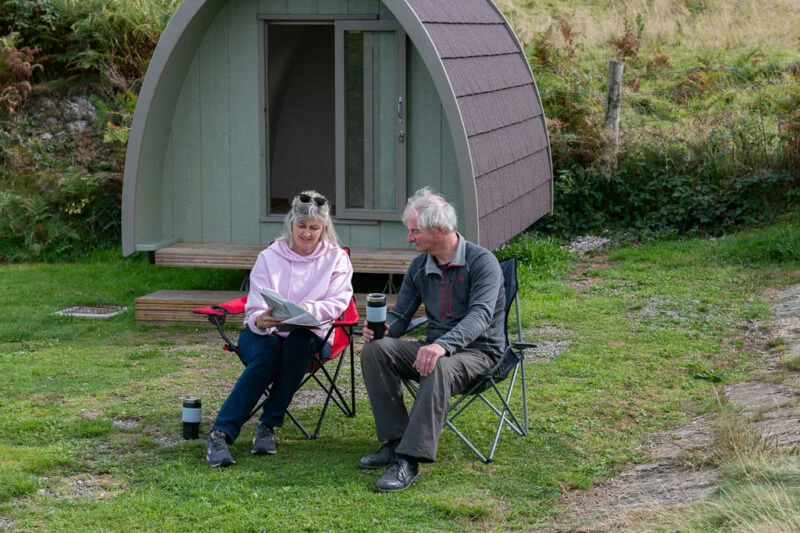 couple sat outside glamping pod lake district
