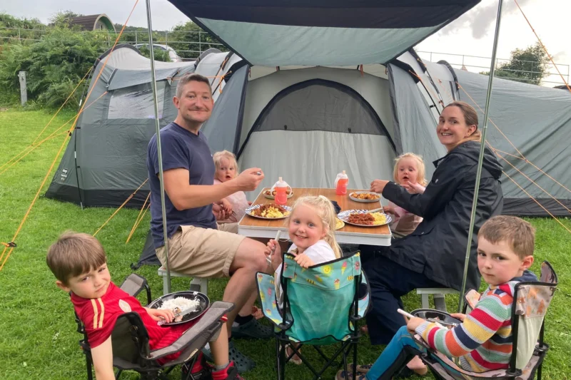 family eating outside tent