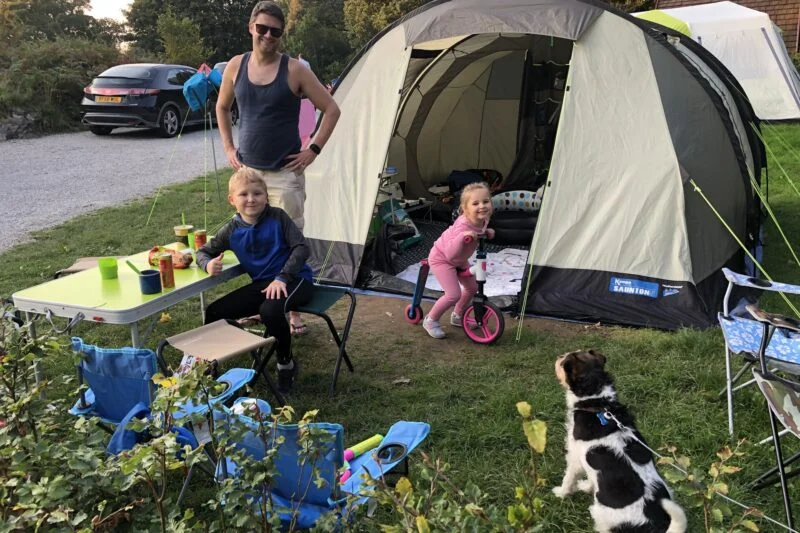 family relaxing outside of tent at park cliffe