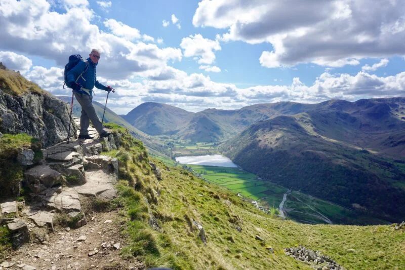 man on a cliff side with view of the lake district