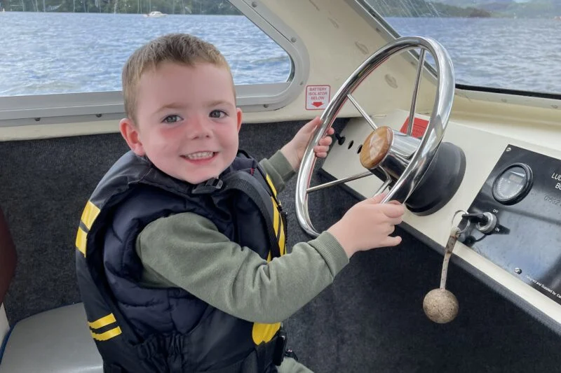 boy driving boat lake district