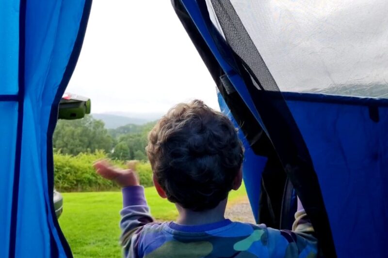 child waving from tent at park cliffe