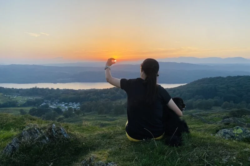 woman pretending to hold te sun at sunset