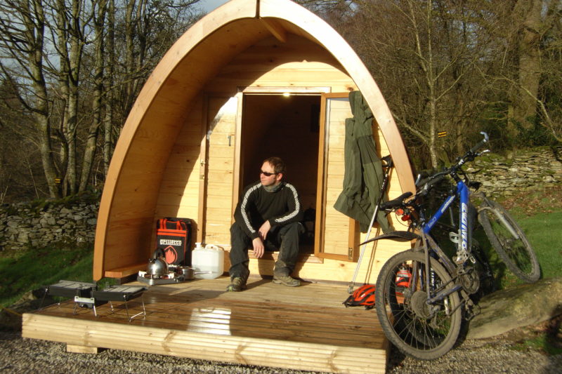man sat outside pod with bike Camping Pods