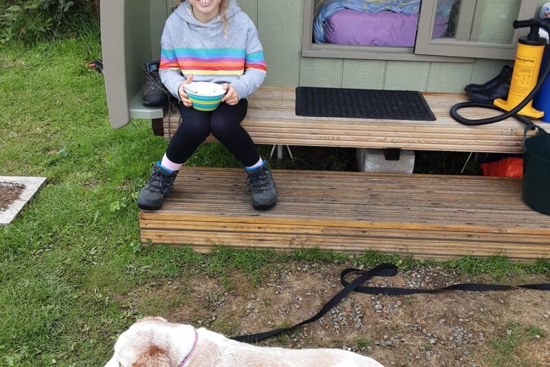 dog and girl outside glamping pod lake district