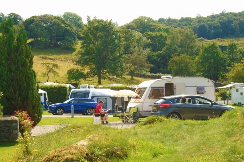 man sat on camping chair touring caravan pitches park cliffe