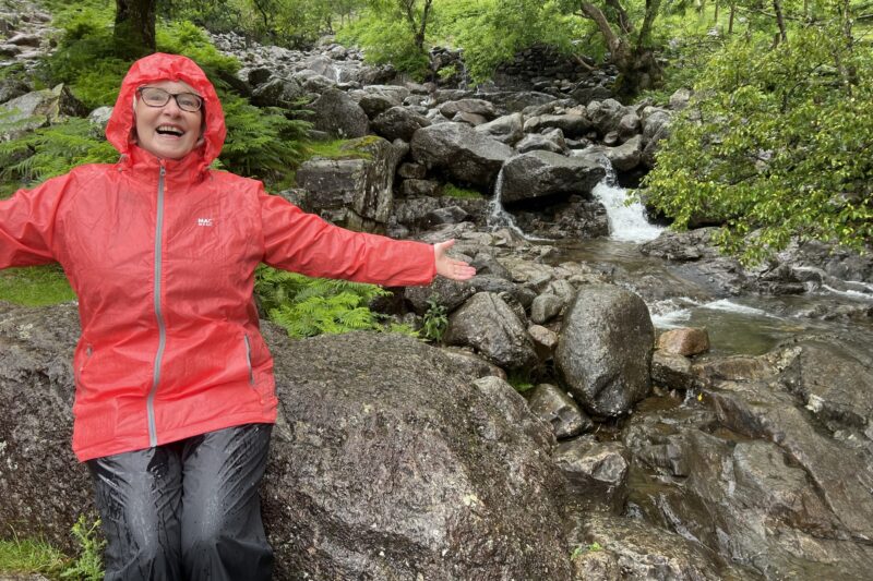 woman sat on a rock in red raincoat